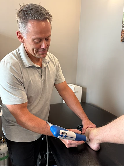 Chiropractor Calgary AB John Scott Performing Shockwave Therapy on Patient John Scott Performing Shockwave Therapy on Patient